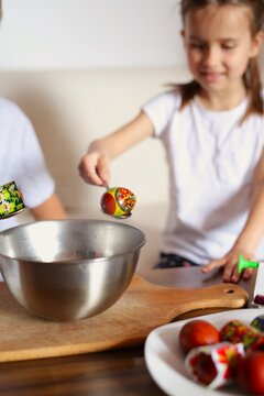 a boy and a girl of seven years old, dressed in white T-shirts, paint eggs for Easter, children do handicrafts, prepare for a family holiday