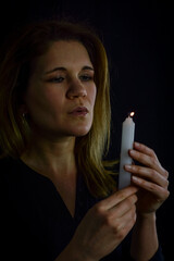 portrait of a beautiful blonde woman blowing out the flame of a candle she is holding