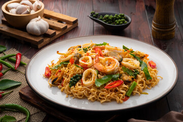 Spicy stir fried instant noodle with shrimp ,green Mussels and squid with thai basil leaves in white plate