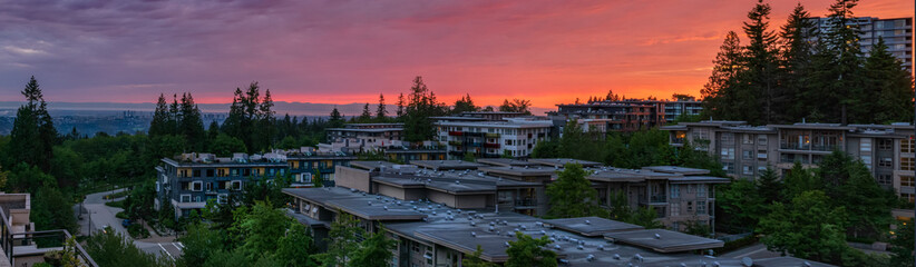 Fototapeta premium Stunning panoramic sunset over rooftops of homes in UniverCity Highlands, Burnaby, BC, as seen from a neighborhood patio.