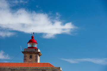 Fototapeta na wymiar old lighthoiuse with red roof in front of blue sky in the south