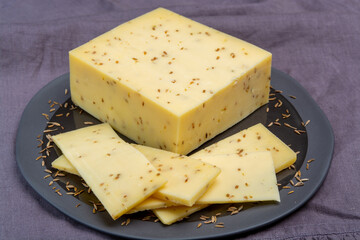 Cheese collection, piece of cow milk Dutch gouda cheese with dried aromatic cumin seeds close up
