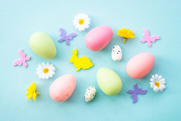 Easter background on blue. Eggs, rabbit, spring flowers and butterflies. Flat lay.