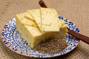 Cheese collection, piece of cow milk Dutch gouda cheese with dried aromatic cumin seeds close up