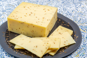 Cheese collection, piece of cow milk Dutch gouda cheese with dried aromatic cumin seeds close up