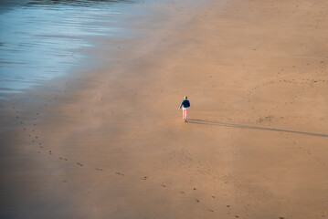 Obraz premium Unrecognized person walking on the sandy beach at sunset. Healthy lifestyle. Exercising outdoors