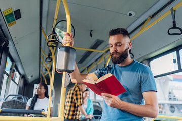 Man reading a book while riding in a bus