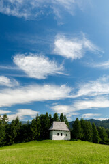 Fototapeta premium Tiny white hut under blue sky on the green hill in Pieniny mountains, Poland