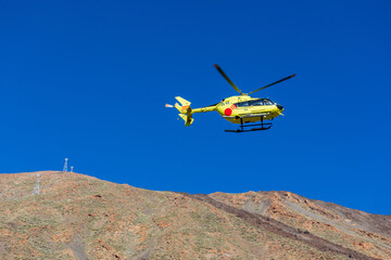 Fototapeta na wymiar Emergency Medical Rescue helicopter in the sky over the Teide volcano, Tererife, Canary Islands, Spain