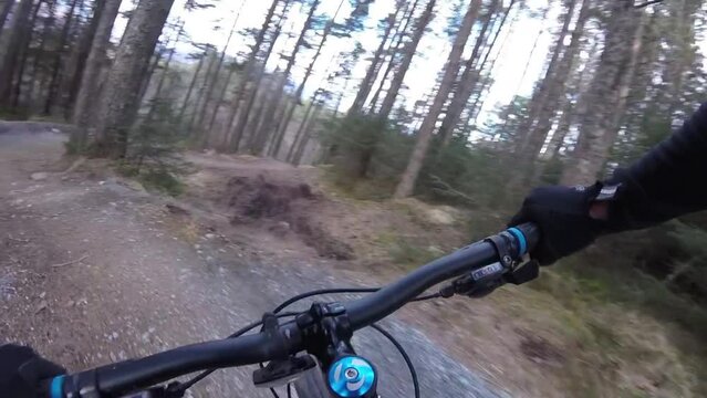 person riding a mountain bike on n a trail through the woods on twists and berms
