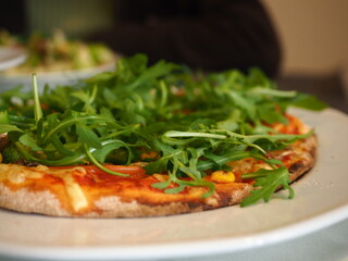 a part of pizza pie with rocket leaves at an Italian restaurant