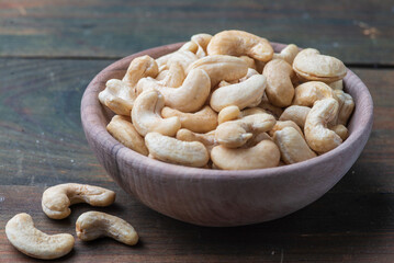 Bowl with raw cashew organic nuts peeled on wooden table rustic table, healthy vegetarian vegan snack Indian walnut Anacardium occidentale sackcloth close-up.