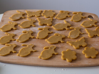 Close-up kneaded ginger dough and carved figurines from it. The shapes of rabbit. Cutting sugar cookie dough with Easter shaped cookie cutters. Preparation for Easter. Holidays baking.