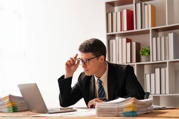 Portrait of businessman inside office with laptop, businessman in glasses and business suit sitting working in the office