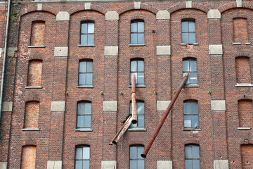 Ceglana ściana starej fabryki w europie z oknami.  - obrazy, fototapety, plakaty