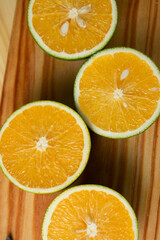 Laranjas cortadas no meio em cima de tábua de madeira e mesa de madeira e pano com estampa de folhas