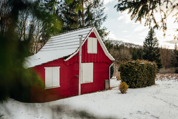 Kleine rote Holzhütte in einer winterlichen Landschaft