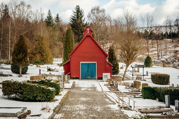 Kleine rote Kirche auf einem Friedhof im Winter mit Schnee
