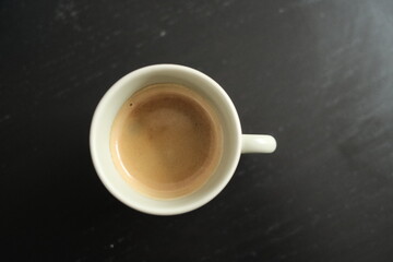 Tasse Espresso steht auf einem schwarzen Tisch