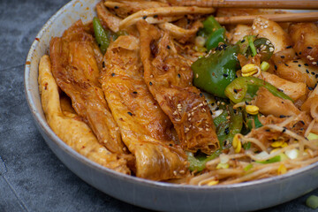 A bowl  consisting of rice cakes,  curd skin, mushroom and bean sprouts as soure of plant based protein
