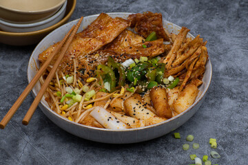 A bowl  consisting of rice cakes,  curd skin, mushroom and bean sprouts as soure of plant based protein