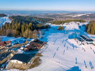 Ski slope, chairlift, skiers and snowboarders in Bialka Tatrzanska ski resort in Poland on Jankulakowski Wierch Mountain in winter. Aerial view in sunset light - 581226528