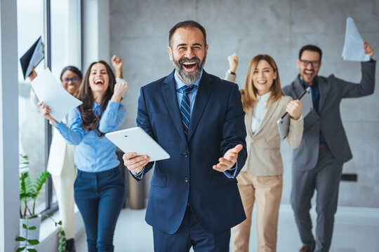 Euphoric excited business team celebrate corporate victory together in office, happy overjoyed professionals group rejoice company victory, teamwork success win triumph concept at conference table