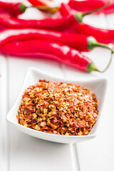 Dry chili pepper flakes. Crushed red peppers in bowl on white table.