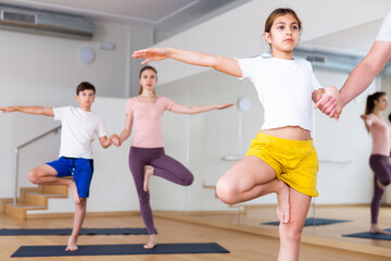 Fototapeta na wymiar Portrait of focused tween girl practicing yoga asanas with family at yoga studio