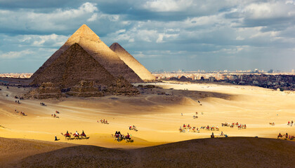 Tourists ride camels on the hills of Giza Plateau near the Great Pyramids. Giza. Western Desert, Giza, Cairo, Egypt