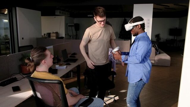 Colleague helps put on vr headset. Testing metaverse world, touching virtual reality subjects. IT Development Team Working on VR Project. Abstract cyber world in office