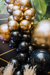 Background, texture of many beautiful round black, golden, colored, balloons on the photo zone against the background of the wall in the interior. Close-up photography, holiday, birthday, wedding.