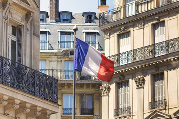 French national flag waving in Paris, the capital of France with residential houses in background