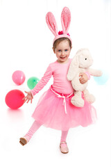 Little child wearing bunny ears on Easter day. Girl with a toy rabbit in her hand