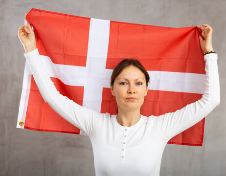 Cheerful young woman holding big Denmark flag in her hands