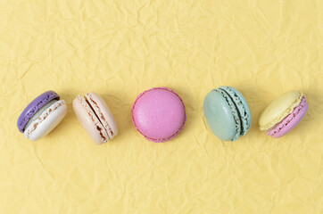 Five macaroons on yellow paper on a blue background.