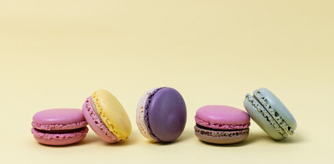 Five colorful macaroons on a yellow background.
