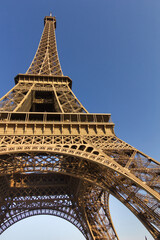 The Eiffel Tower in Paris in warm sunlight of evening sun with blue sky in the background