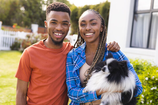 Portrait of happy african american couple holding pet dog and smiling, copy space