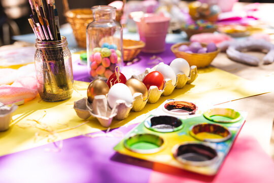 Close up of selection of colorful easter eggs and paints on table