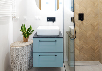 Ceramic washbasin with tap, wooden tiles in the shower with glass and round mirror with led lights...