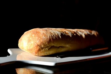 baguette on board German baguette on white board isolated. Top view or french bread. Bakery Freshly baked baguette or multigrain loaf bread Dark background porcelain board