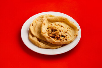 Egyptian bread Aish Baladi. A lot of fresh bread lies on the red table