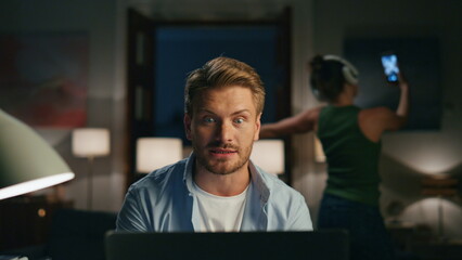 Fototapeta premium Attentive man work computer at home closeup. Funny woman dancing listening music