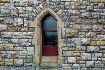 Fototapeta na wymiar A small, beautiful gothic-style window on a stone castle wall