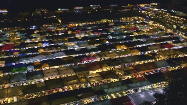 Panning over colorful Asian market tents and food stalls at night. 
