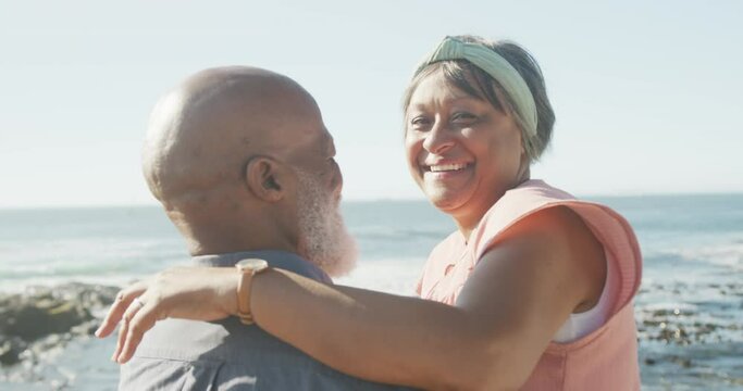 Portrait of happy senior african american couple embracing on promenade by the sea, slow motion