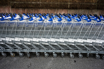 Long rows of empty shopping carts waiting for customers by a shopping mall.