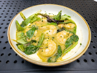 A plate of vegetables, shrimp and grits on a table for lunch