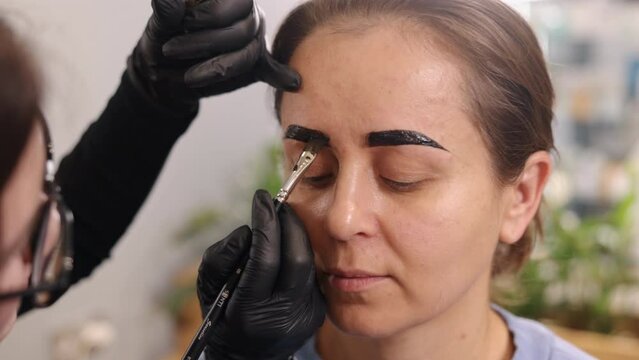 styling eyebrows, Professional makeup, procedure of lamination. Young woman undergoing eyebrow correction procedure in beauty salon, eyebrow microblading concept, painting eyebrows with paint.